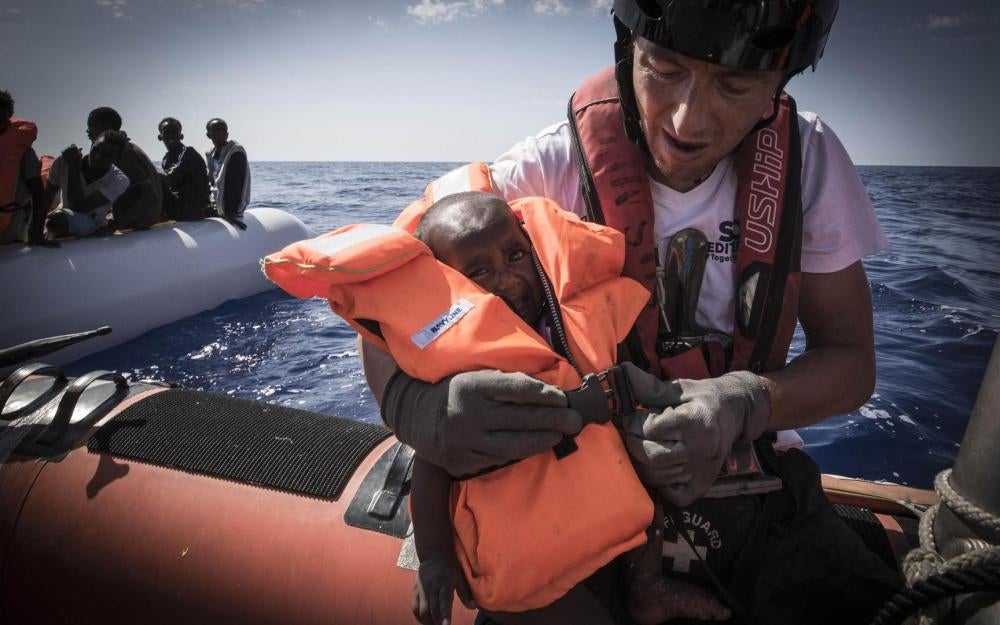 SOS MEDITERRANEE rescuer Dragos Nicolae puts a life jacket on a young child during a rescue operation in international waters off of Libya. October 11, 2017.