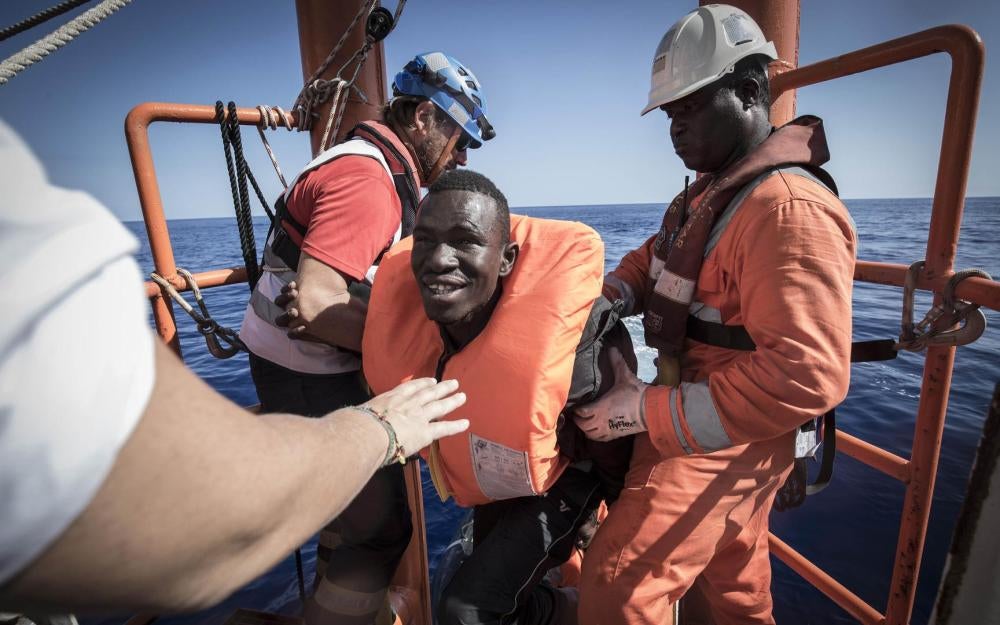 Aquarius crew members help a man onto the ship after a rescue. October 11, 2017.