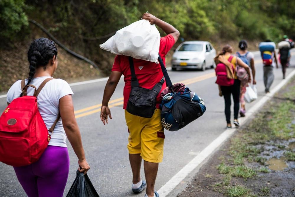 Um grupo de migrantes venezuelanos que viajam a pé carrega seus pertences após sair da cidade fronteiriça de Cucuta, Colômbia, em 29 de julho de 2018. Todo dia, centenas de venezuelanos iniciam a jornada a pé em direção a outras cidades da Colômbia, Equad