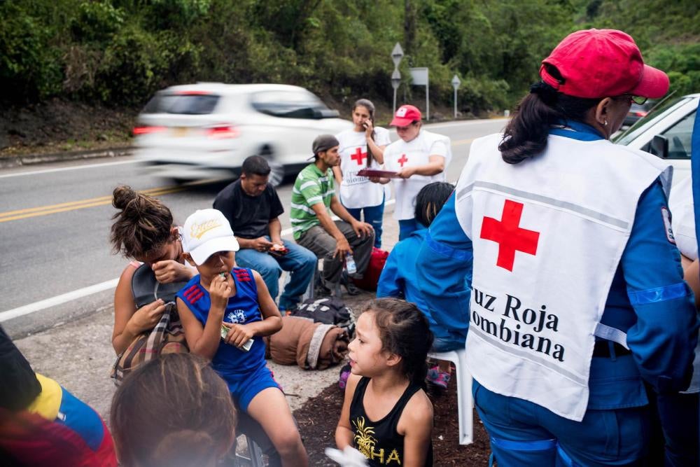 Venezuelanos viajando a pé param para um breve descanso numa estação da Cruz Vermelha colombiana, onde recebem água e lanches, em 29 de julho de 2018. Todo dia, centenas de venezuelanos iniciam a jornada a pé em direção a outras cidades da Colômbia, Equad