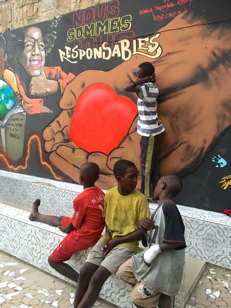 Talibé children take a break at the Maison de la Gare children’s center in Saint-Louis, Senegal, January 14, 2019. Maison de la Gare is a non-profit organization and shelter that supports talibés. The text on the mural reads, in French: “We are all respon