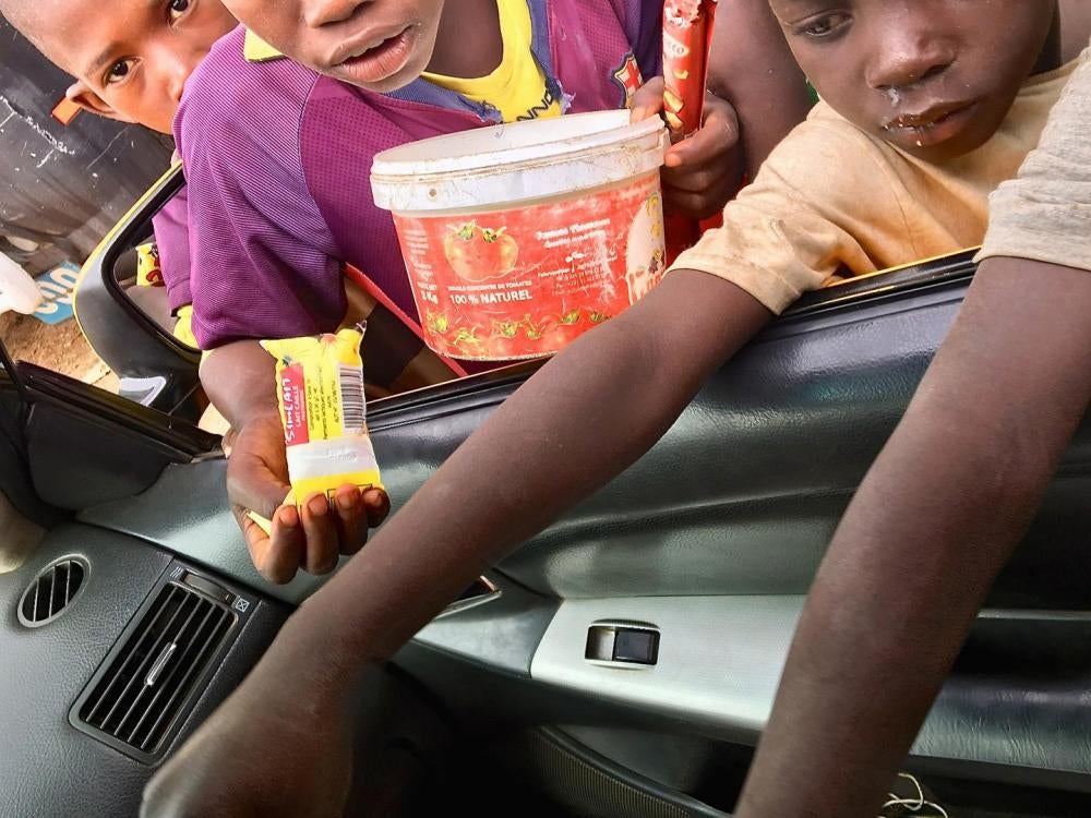 Des enfants talibés mendient à la portière d'une voiture à Dakar, au Sénégal, le 19 juin 2018. 