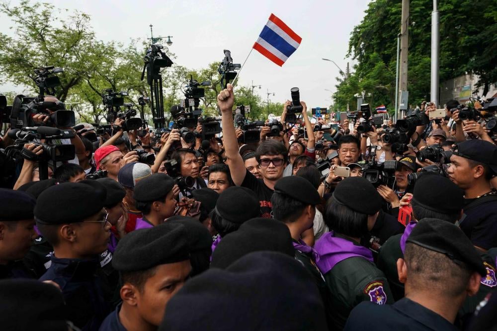 Ativista pró-democracia Rome Rangsiman segura bandeira da Tailândia, enquanto manifestantes contrários ao governo se juntam para exigir que o governo militar realize eleições gerais antes de novembro. Bangcoc, 22 de maio de 2018.