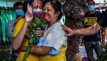 A woman holds up a three finger salute