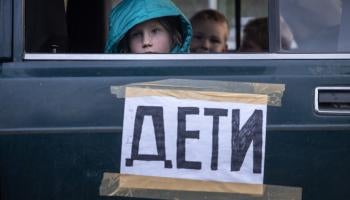 Children from Mariupol, Ukraine, look out the window of their family’s car, marked with the word “children,” after arriving at an evacuation point for people fleeing areas under Russian control.