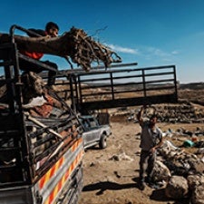 An individual on a truck speaks to a standing individual. 