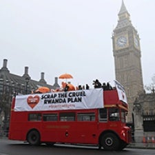 British bus drives through street with a sign reading 