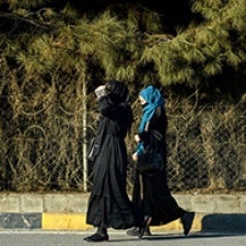 Two figures walk onto street, wearing religious clothing. 
