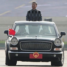 Man stands in car with Chinese flag. 