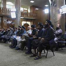 Many figures sit in a line. 