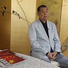 Jimmy Lai sits at table and faces camera.