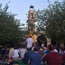 Large group of people gather in front of statue. 