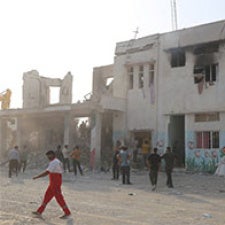Figures walk through streets of Iran. 