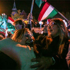 Crowds hold large Hungarian flags. 