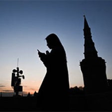 Silhouette of figure holding cell phone. 