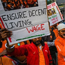 Protester holds sign reading "Ensure Decent Living Wage".
