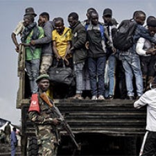 A man stands guard as people board a truck in DRC