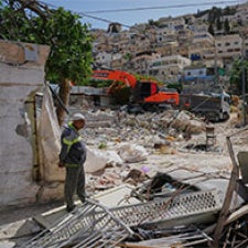 Man stands overlooking the rubble of a residential area