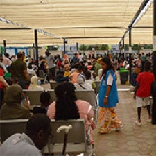 People sitting in crowd, under large tent 