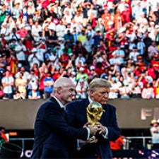 Two men stand on stage, holding trophy 