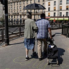 Two people walking together, holding an umbrella 