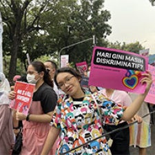 A young protester holds a rainbow sign 