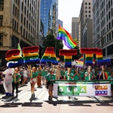 People at a rally holding rainbow flags and banners 