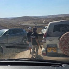 Figures stand between cars. 