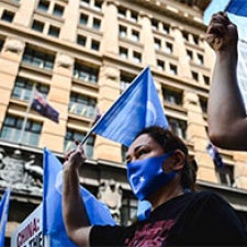 Protesters hold blue flags in the air. 