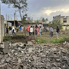 A group of people stand beside rubble. 