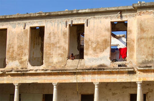 A woman looks out a window from an abandoned building 