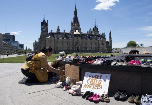A woman kneels in front of a memorial