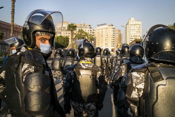 A group of uniformed police with riot gear stand on the street