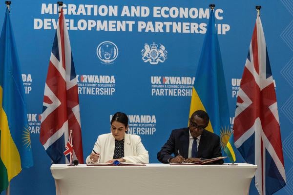 Then-British Home Secretary Priti Patel (L), and Rwandan Minister of Foreign Affairs and International Cooperation Vincent Biruta sign an agreement