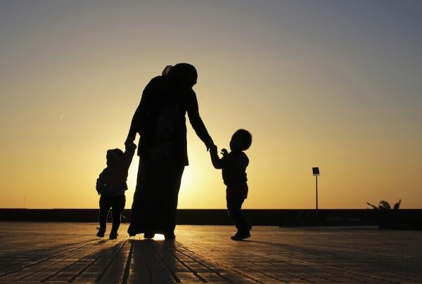 A woman walks with her two children at sunset near the seashore in Benghazi.