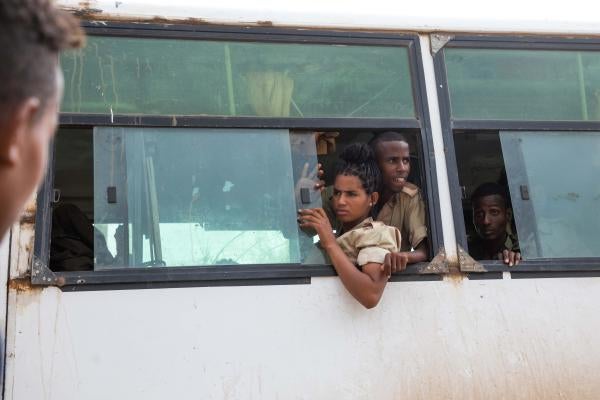 Soldiers lean out of a bus window