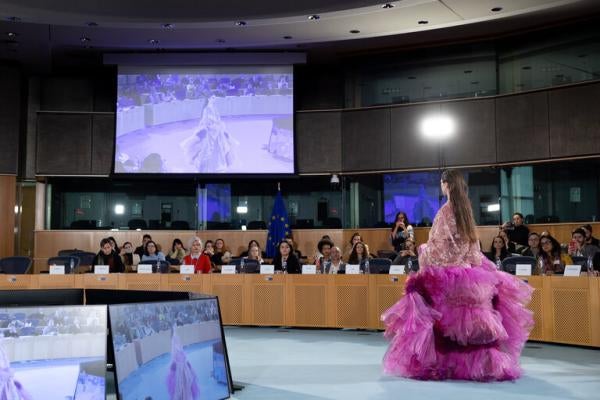 A model walks in front of a panel of speakers in the European Parliament