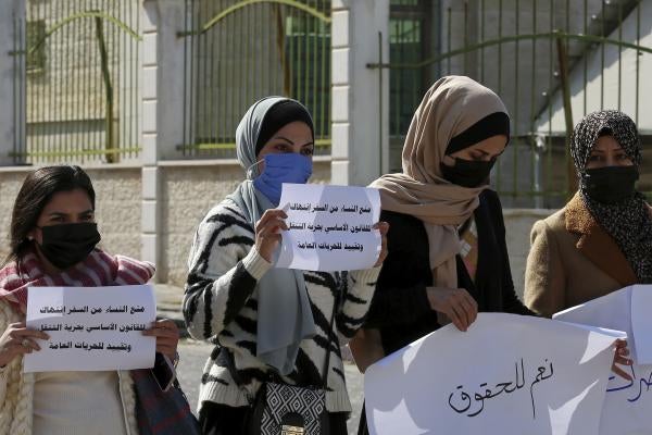 Women hold signs in Arabic during a protest 