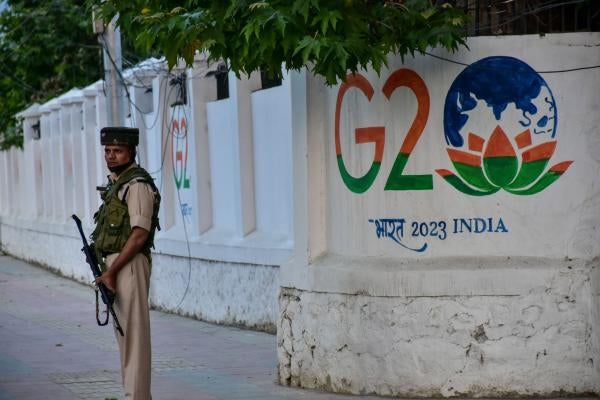 An Indian paramilitary trooper stands in front of a wall painted with the G20 logo on May 23, 2023, in Kashmir, India. 