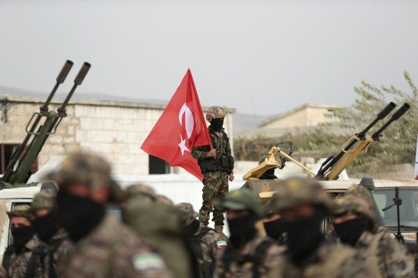 An unidentifiable soldier holds a Turkish flag