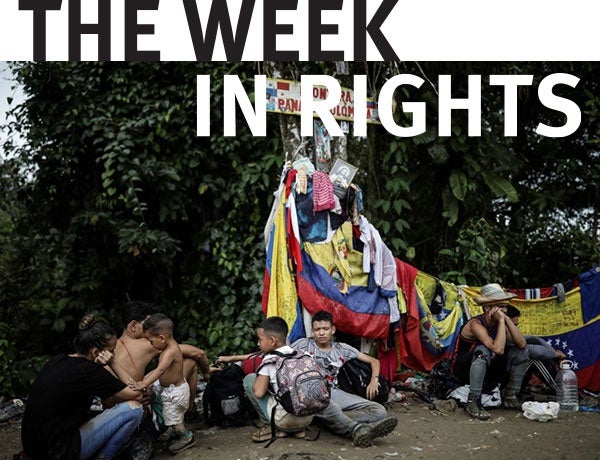 Families sit beside clothes near the Darien Gap. 