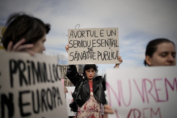 A woman holds a banner that reads "Abortion is an essential public health service" at a rally