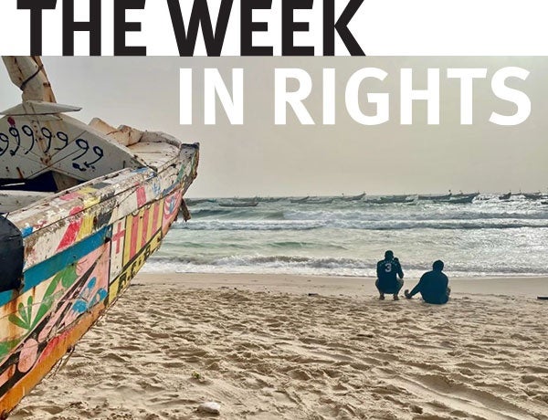 Two figures walk on beach. 