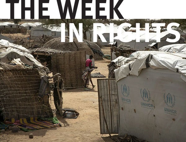 Figure stands amongst housing structures. 