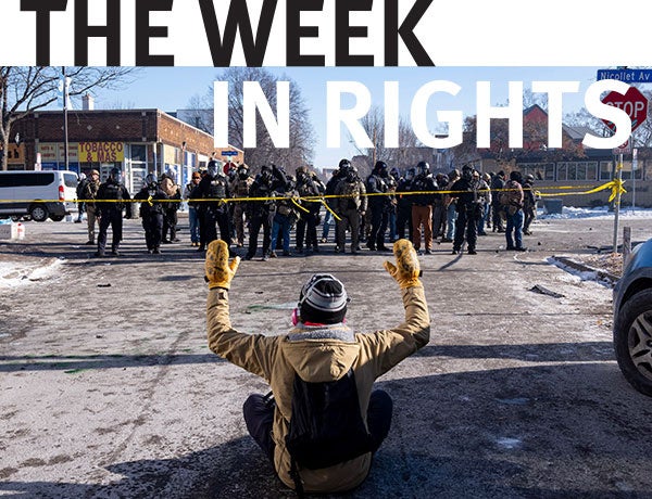 A protester sits on the street with his arms up in front of federal agents and Minneapolis Police on W. 27th St and Nicollet Avenue in south Minneapolis after Alex Pretti was fatally shot by federal agents in the area 
