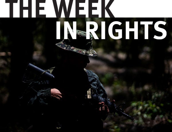 Individual in military garb points gun towards ground. 