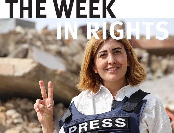 Journalist faces camera and raises two fingers to form a peace sign.