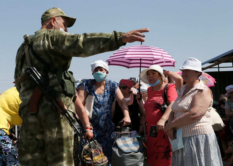 People listen to an armed man with the self-proclaimed Donetsk People's Republic.