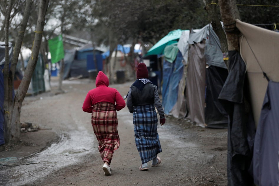 Migrant women walk inside a migrant encampment in Matamoros, Mexico, February 18, 2021.