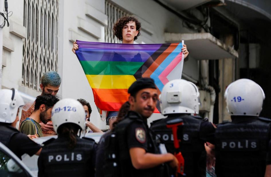A demonstrator holds a rainbow flag in front of police officers as people try to gather for a Pride parade, which was banned by local authorities, in central Istanbul, Turkey June 26, 2022. REUTERS/Dilara Senkaya